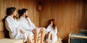 A man and 2 women in robes enjoying a sauna